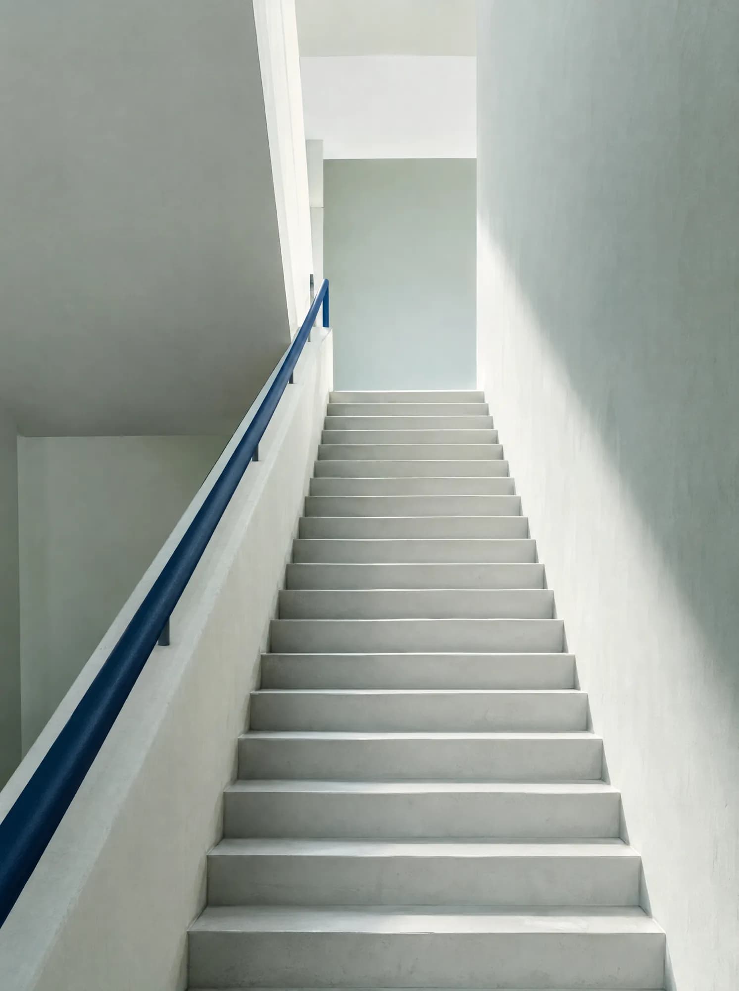 A precise white staircase with a navy handrail